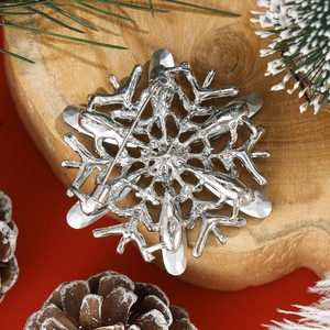 Silver snowflake brooch with rhinestones shown from the back on a rustic wooden base