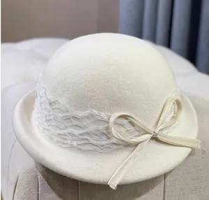 Detail of cream white wool felt cloche hat with lace mesh and elegant ribbon bow decoration