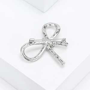 Detailed back view of a silver bow brooch showing the secure pin fastener and metal texture