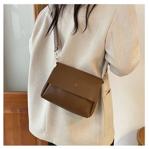Brown leather crossbody bag with geometric woven strap and metallic buckle detail