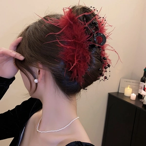 Close-up of a large hair claw clip with dark red feathers and black beaded accents