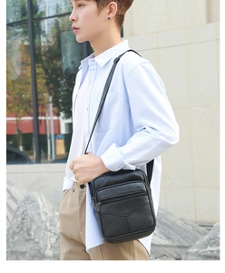 Detail view of black leather crossbody bag featuring dual zippers and adjustable shoulder strap