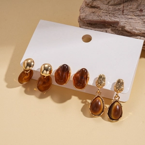 Close-up of six-piece resin earring set in amber brown and gold on a display card