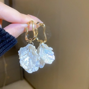 Detailed close-up of golden hoop earrings featuring iridescent shell petal charms