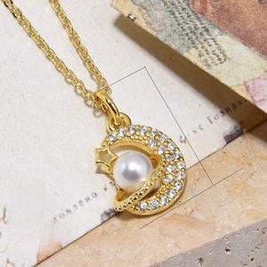 Macro detail of a gold-plated moon and star pendant with zircons and imitation pearl