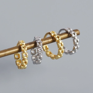 Detailed macro view of S925 silver and gold watchband style geometric hoop earrings