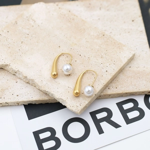 Detail view of 18k gold-plated teardrop earrings with white pearls on stone texture