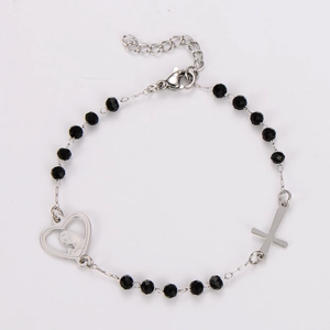 Détail du pendentif cœur avec relief et croix sur un bracelet de perles noires à facettes