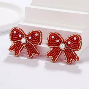 Detail of red bow beadwork earrings with handmade seed beads and small white pearls
