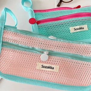 Detail of dual-layer mesh pencil cases in pink and mint green with round zippers