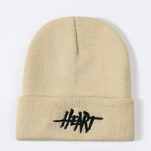 Detail of beige knit beanie showing textured ribbed weave and black HEART embroidery