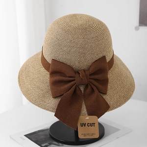 Detailed texture of straw sun hat featuring a wide brown ribbon and UV protection tag