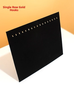 Detail view of 17 gold hooks on a black velvet necklace and jewelry display board