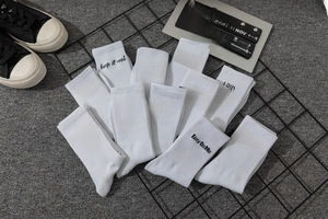 Detail of white mid-tube cotton socks featuring ribbed cuffs and black letter slogans