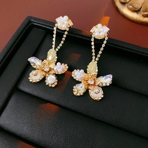Detail of floral earrings with shimmering crystals and white pearls on a black display