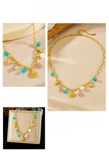 Detail of gold shell and conch pendants with pearl and blue bead on a beach style necklace