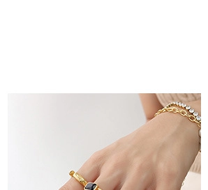 Detail of 18K gold ring with black gemstone and layered chain bracelets on wrist