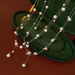 Detail of gold and silver pearl necklaces with round pendants in a green jewelry box