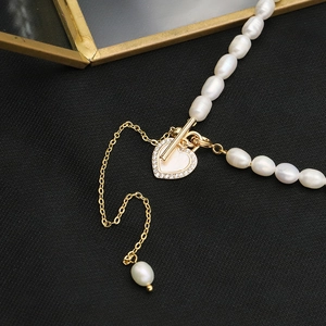 Macro detail of natural freshwater pearl necklace with sparkling gold heart pendant