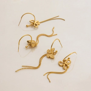Detail of golden stainless steel bow and butterfly earrings with elegant tassel chains