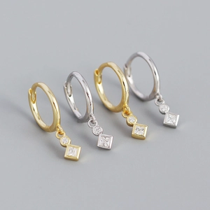 Detail of gold and silver hoop earrings with round and square zircon geometric charms