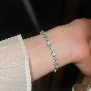 Détail du bracelet en œil de chat vert clair avec zircone sur poignet féminin