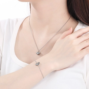 Close-up of silver stainless steel heart necklace and bracelet set worn by a model