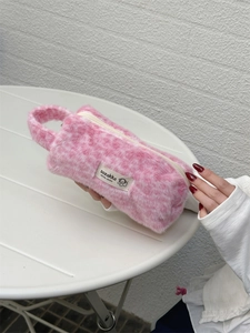 Detailed close-up of a pink faux fur plush pencil case with zipper and carry handle