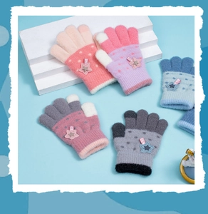 Flat lay of knit kids star gloves in pink, purple, blue, and gray colors on blue background