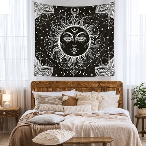 Detail of bohemian sun and moon tapestry hanging above a bed with minimalist wood furniture