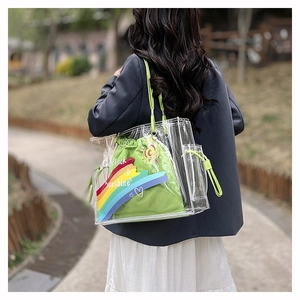 Outdoor shot of a clear rainbow PVC tote bag with a green canvas inner pouch