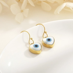 Macro view of heart-shaped evil eye earrings with white shell inlay on ceramic edge