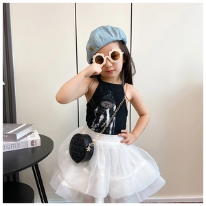 Close-up of a girl wearing a black quilted round chain bag and stylish tutu outfit