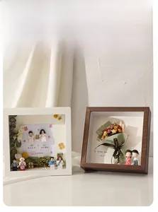 Detailed shadow box frame with wooden finish showcasing dried flowers and miniature figures