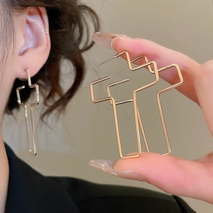 Détail des boucles d'oreilles géométriques croisées en métal au design minimaliste