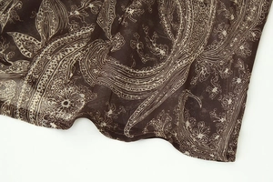 Gros plan du motif paisley vintage sur un tissu en mousseline marron translucide