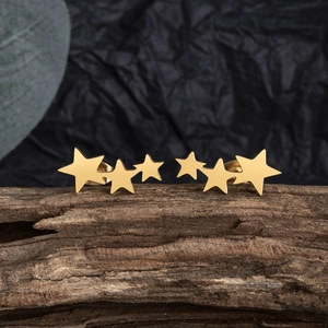 Macro shot of three-star gold stainless steel stud earrings on a natural wood stand