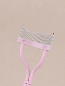 Detail of pink eyelash comb featuring fine stainless steel teeth for shaping and defining