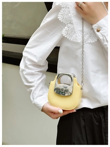 Close-up of small yellow crossbody bag with silver chain strap worn with lace shirt