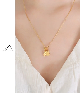 Close-up of golden stainless steel necklace with cute rabbit and carrot pendants on model