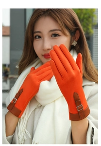 Detail of orange suede winter gloves featuring touch-screen fingertips and leather buckle