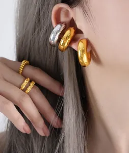 Close-up of polished gold ear cuffs and textured golden rings on a female model