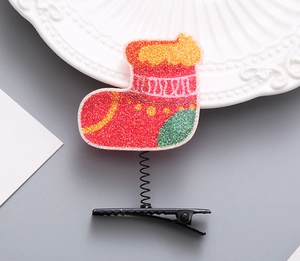 Detail einer Weihnachtsstrumpf-Haarklammer mit rotem und grünem Glitzer und Feder