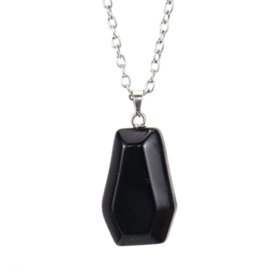 Detailed view of coffin shaped black obsidian pendant with faceted geometric edges and chain