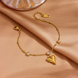 Detail of a golden stainless steel heart bracelet with rhinestones on silk fabric