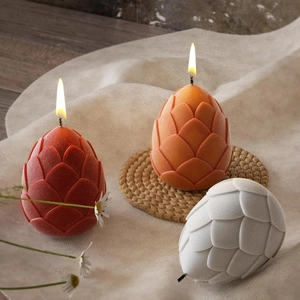 Pinecone shaped scented candles in red, orange and white with textured scales