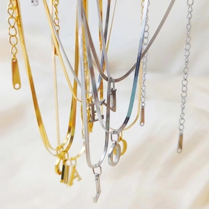 Detailed view of 26 alphabet pendants on gold and silver snake bone necklaces