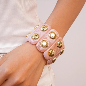 Detail of pink marble acrylic stretch bracelet with large gold dome metal studs for women