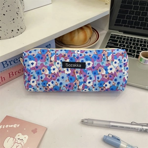 Macro view of vintage floral fabric pencil case with black brand label on desk