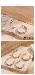 Artistic detail of C-shaped twisted weave earrings in gold and silver on stone